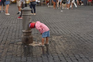 Un bimbo beve l'acqua da una fontanella romana