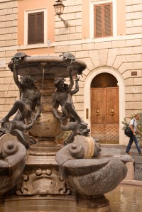 Un uomo passa alle spalle della fontana delle tartarughe